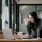 Beautiful Asian woman celebrate with laptop, successful business startup small business concept.