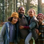 Happy black family enjoying in camping weekend in the woods and looking at camera.
