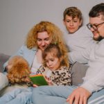 happy family with children, dog home on couch planning joint business, checking schedule in diary