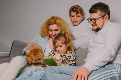 happy family with children, dog home on couch planning joint business, checking schedule in diary