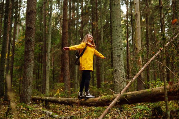 Happy tourist with backpack walking on log in forest, balancing: healthy lifestyle, harmony concept