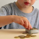 Kid with Saving Money for Education Concept. Child putting Coin into a Box