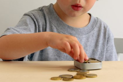 Kid with Saving Money for Education Concept. Child putting Coin into a Box
