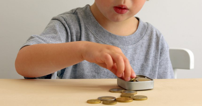 Kid with Saving Money for Education Concept. Child putting Coin into a Box