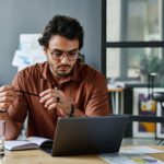 Young serious businessman in shirt and eyeglasses networking